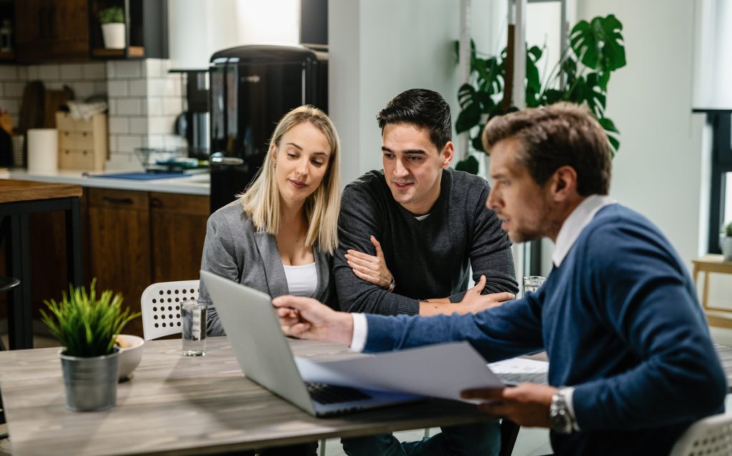 In this image, a consultant from The Smart Blinds Co. is seen discussing a proposal for custom roller blinds with a couple. The consultant is guiding the couple through the details of the proposal using a laptop, showing them different fabric options and features tailored to their home's needs. The personalised consultation service focuses on helping the couple make an informed decision about enhancing their home's aesthetic and functionality with custom roller blinds.